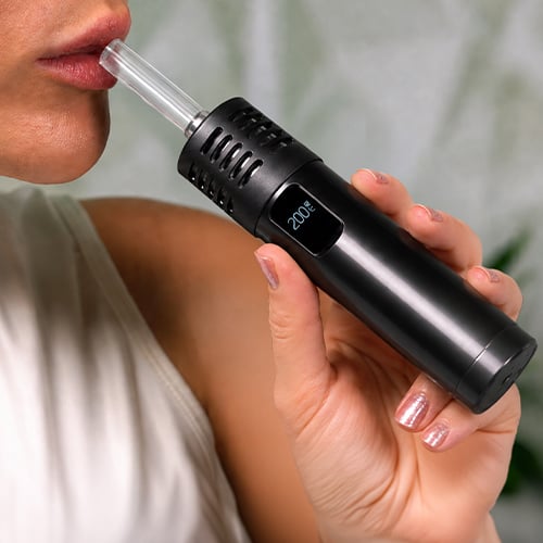 Woman in the process of using the Arizer Air Max vaporizer.