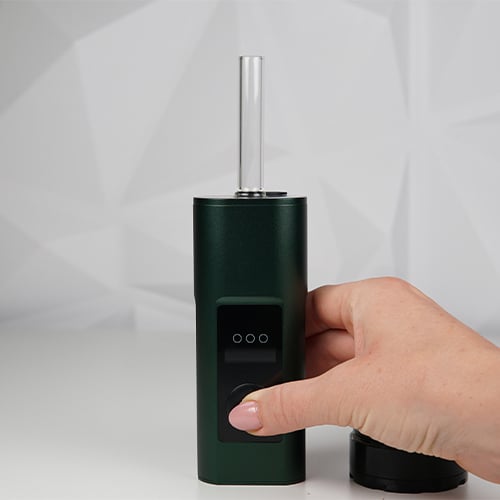 Hand holding Arizer Solo 3 vaporizer on table with glass tube at the top