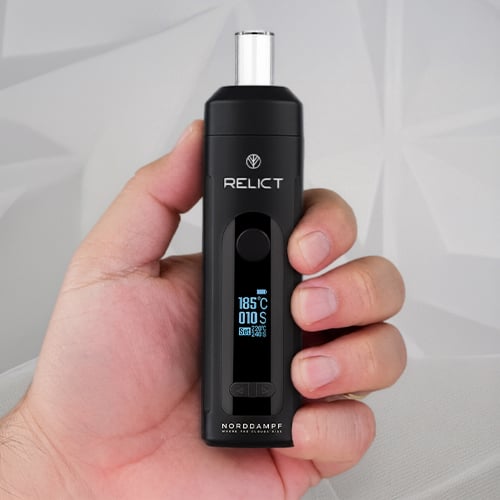 Hand holding a Norddampf Relict vaporizer.