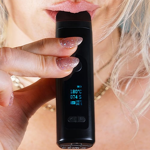 Woman in the process of using the Tronian Milatron vaporizer.