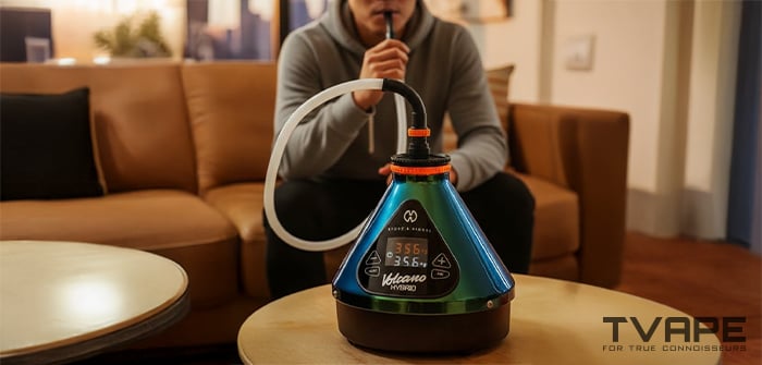 A man is inhaling from the Volcano Hybrid desktop vaporizer (evergreen edition)