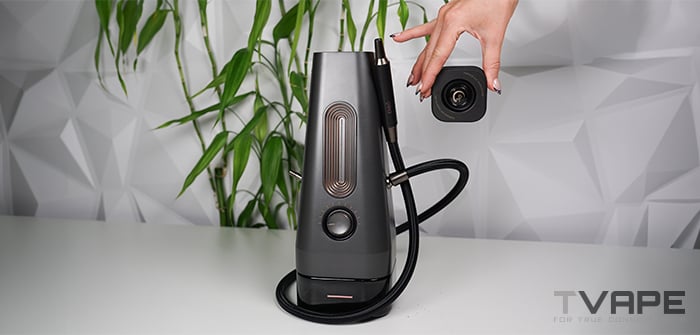 Hand lifting the removable Glass ThermoCap off the AirVape Enso 2026 electric shisha, showing the open heating chamber and attached vapor hose